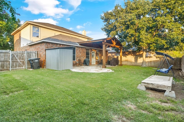 rear view of property with a lawn, a patio, brick siding, and a fenced backyard