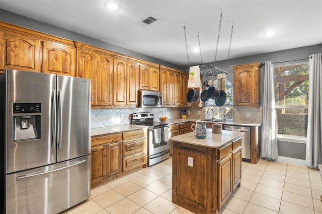 kitchen featuring appliances with stainless steel finishes, brown cabinetry, a sink, and visible vents