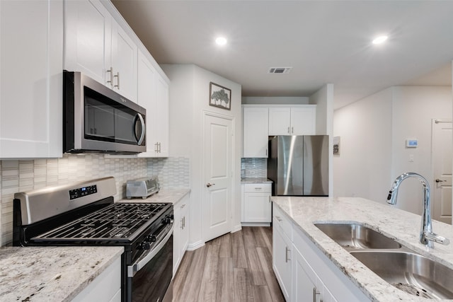 kitchen featuring visible vents, appliances with stainless steel finishes, a sink, white cabinets, and light wood-style flooring