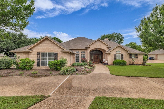 ranch-style home featuring roof with shingles, a chimney, a front lawn, and brick siding