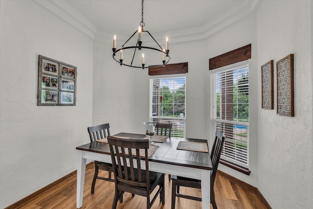 dining area with an inviting chandelier, baseboards, a textured wall, and wood finished floors