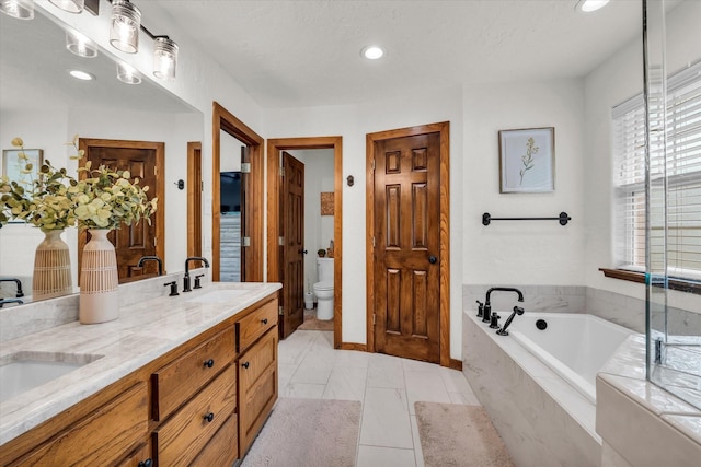 bathroom with a sink, double vanity, toilet, recessed lighting, and a garden tub