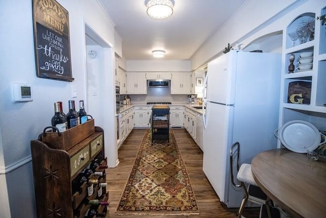 kitchen with light countertops, dark wood finished floors, freestanding refrigerator, white cabinetry, and stainless steel microwave