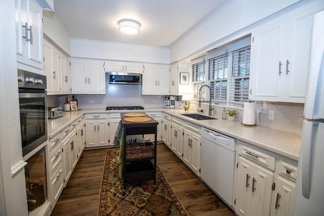 kitchen with dark wood-style flooring, white appliances, light countertops, white cabinets, and a sink