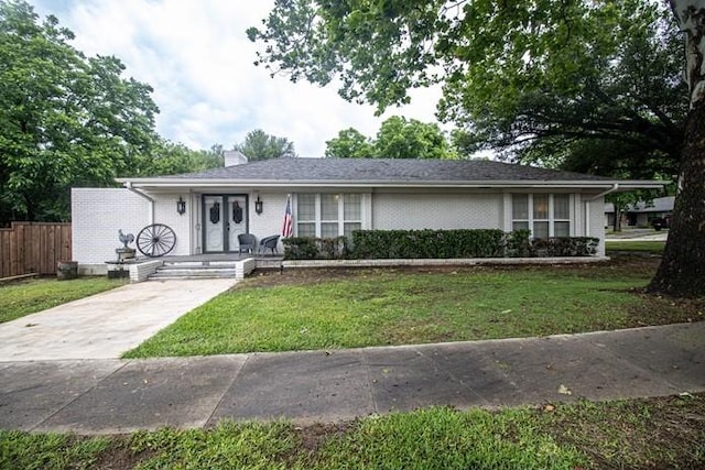 ranch-style house with fence, a chimney, brick siding, and a front yard
