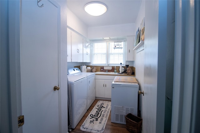 washroom with a sink, washer and clothes dryer, cabinet space, and wood finished floors