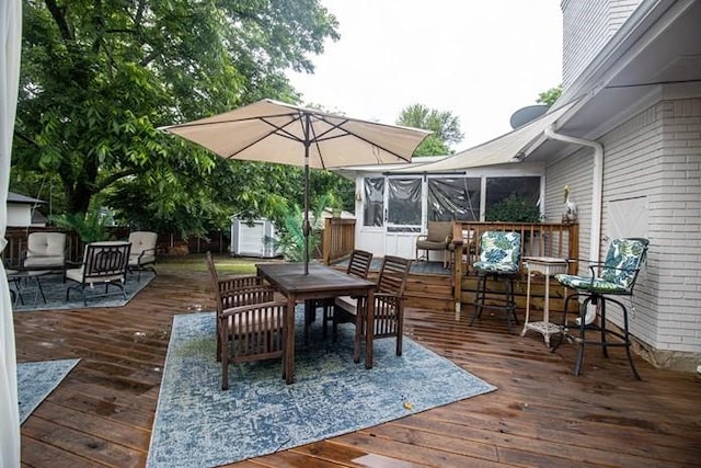 wooden terrace with a sunroom, outdoor dining area, and a storage unit