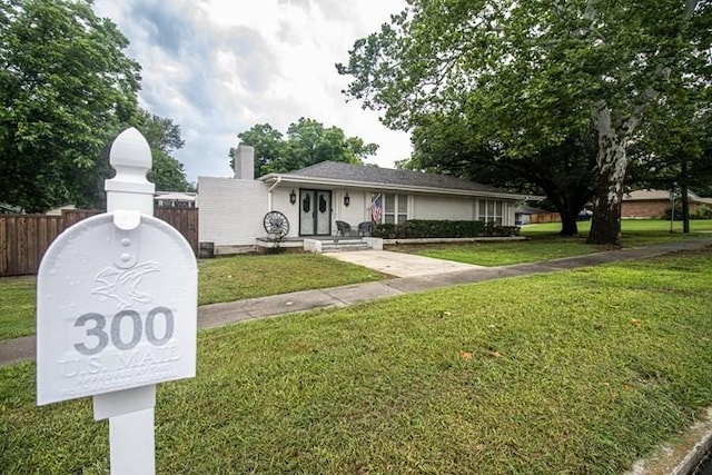 view of front of property with fence, a chimney, and a front yard