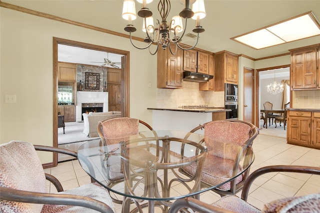 dining space featuring visible vents, ornamental molding, a fireplace, ceiling fan with notable chandelier, and light tile patterned floors