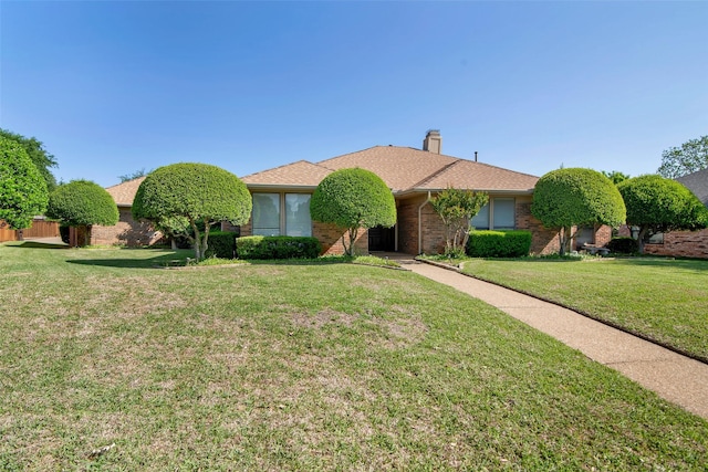 single story home with a chimney, brick siding, and a front yard