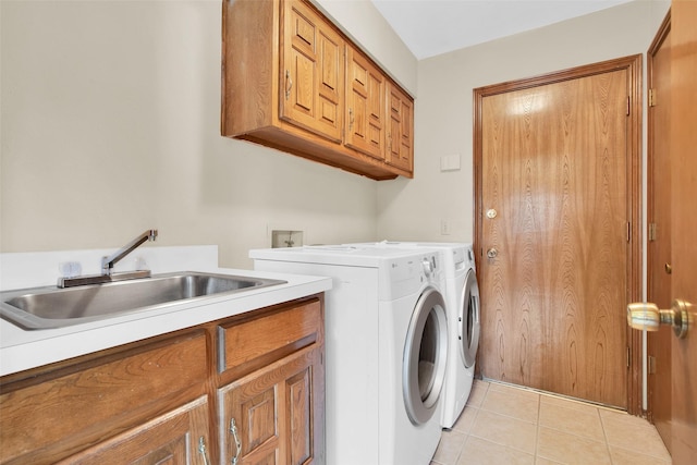 clothes washing area with a sink, light tile patterned floors, cabinet space, and washer and dryer