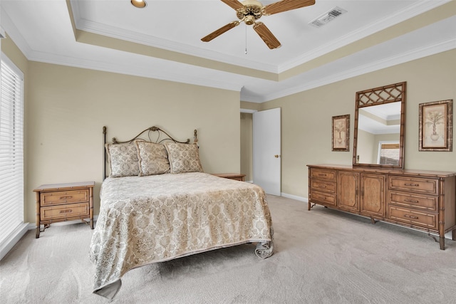 bedroom featuring a tray ceiling, visible vents, light carpet, and multiple windows