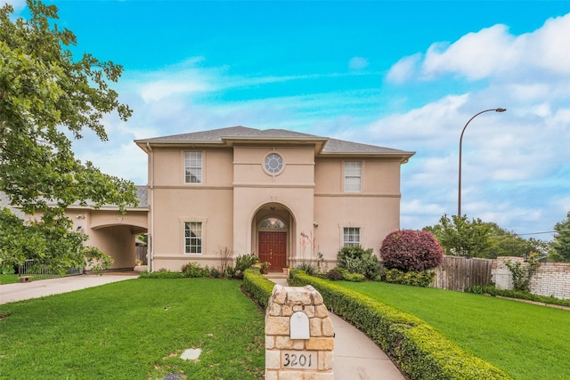 mediterranean / spanish-style home featuring fence, a front lawn, and stucco siding