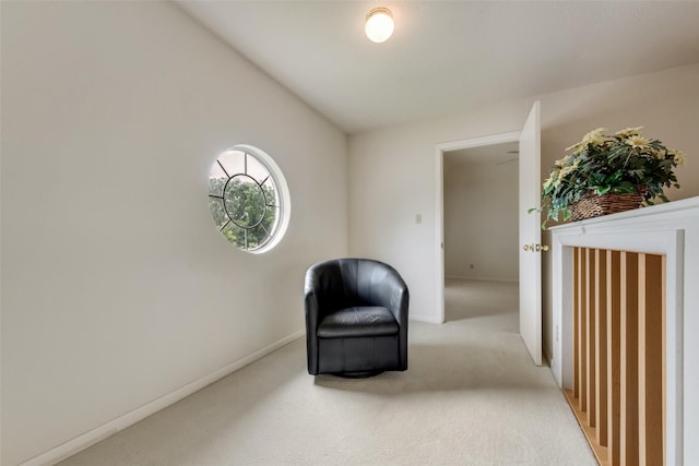 sitting room featuring baseboards and light carpet