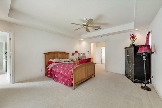 bedroom with visible vents, ceiling fan, a tray ceiling, and light carpet