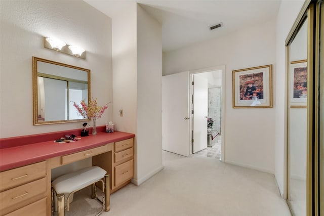 interior space featuring visible vents, baseboards, built in desk, and light colored carpet