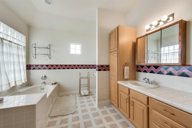 full bathroom with vanity, a wainscoted wall, a bath, and tile walls