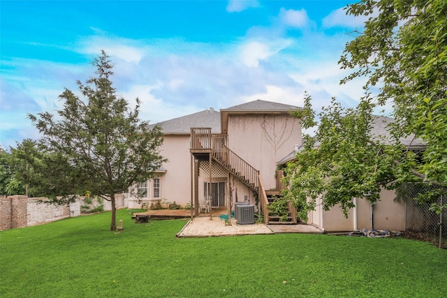 back of property with stairs, a fenced backyard, a lawn, and stucco siding