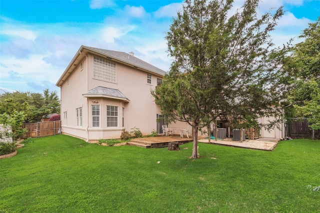 back of property with a fenced backyard, a wooden deck, stucco siding, and a lawn