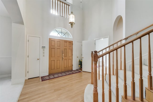 foyer featuring stairs, a towering ceiling, and wood finished floors