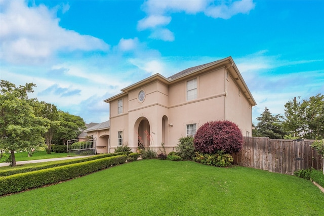 mediterranean / spanish-style home featuring fence, a front yard, and stucco siding