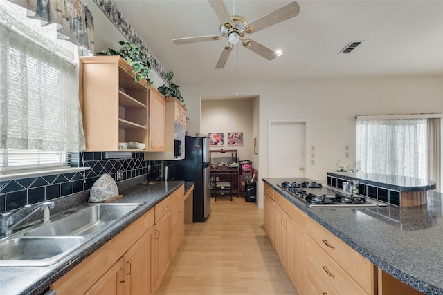 kitchen featuring open shelves, dark countertops, a sink, light brown cabinets, and stainless steel appliances