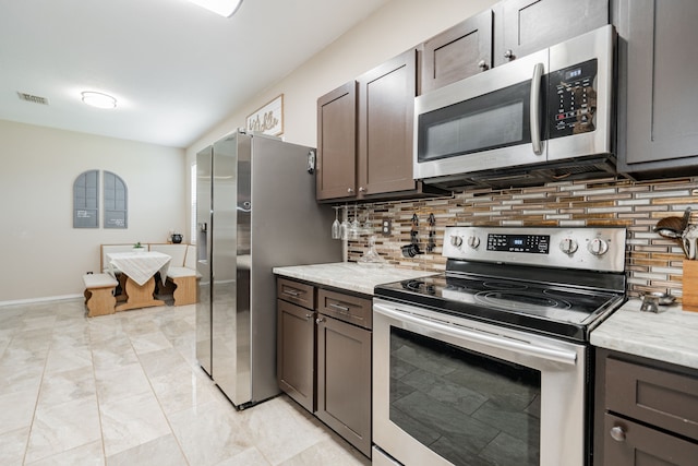 kitchen with appliances with stainless steel finishes, baseboards, backsplash, and marble finish floor