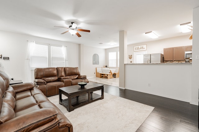living room featuring baseboards, a ceiling fan, and hardwood / wood-style floors