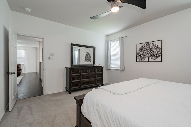 bedroom with ceiling fan, light carpet, and baseboards