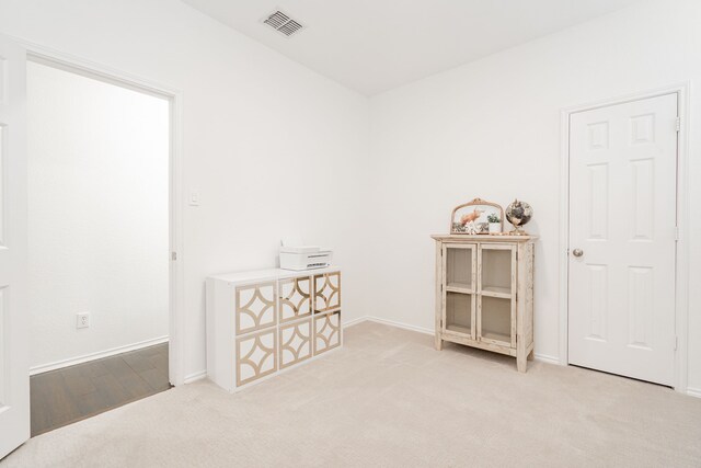 interior space with baseboards, light colored carpet, and visible vents