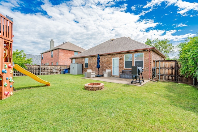 back of house featuring roof with shingles, a patio area, brick siding, a fenced backyard, and a fire pit