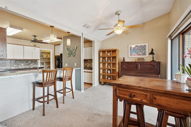 dining space featuring light colored carpet, a ceiling fan, and visible vents