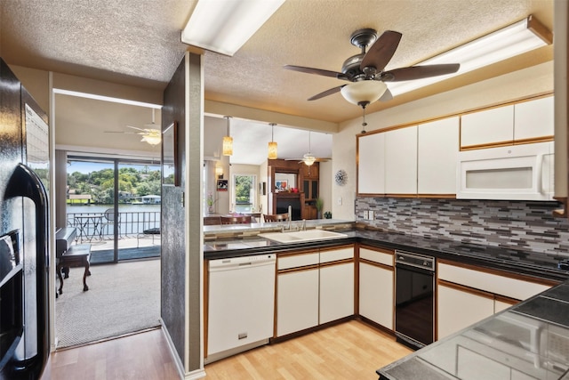 kitchen featuring ceiling fan, a textured ceiling, a sink, black appliances, and light wood finished floors