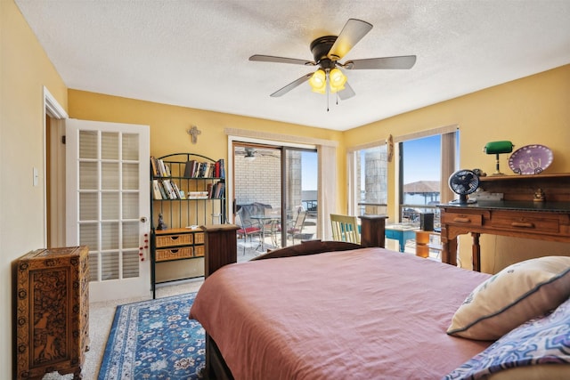 carpeted bedroom with access to outside, a textured ceiling, and a ceiling fan