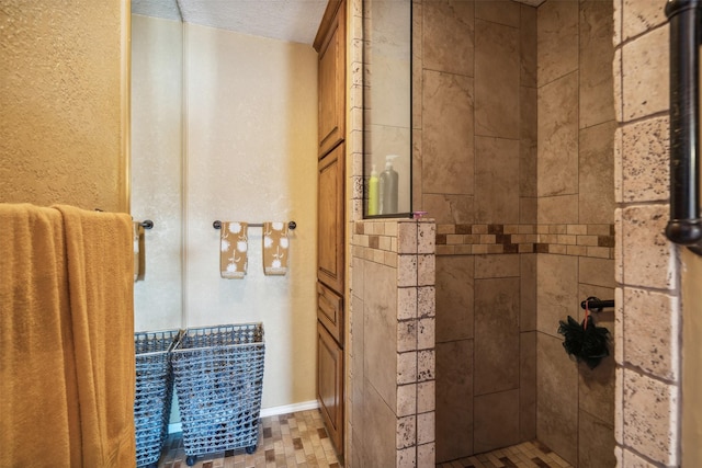 full bathroom with baseboards, a textured ceiling, and tiled shower