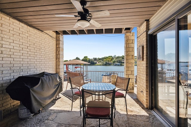balcony featuring a water view, a ceiling fan, outdoor dining space, and a grill