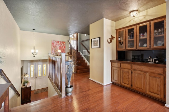 interior space with a notable chandelier, stairs, a textured ceiling, and wood finished floors