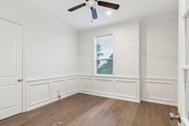 spare room featuring crown molding, a ceiling fan, wainscoting, and wood finished floors