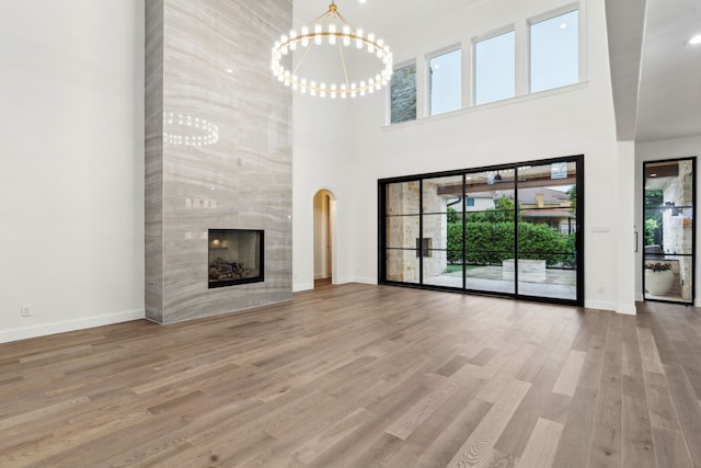 unfurnished living room with an inviting chandelier, a high ceiling, and a wealth of natural light