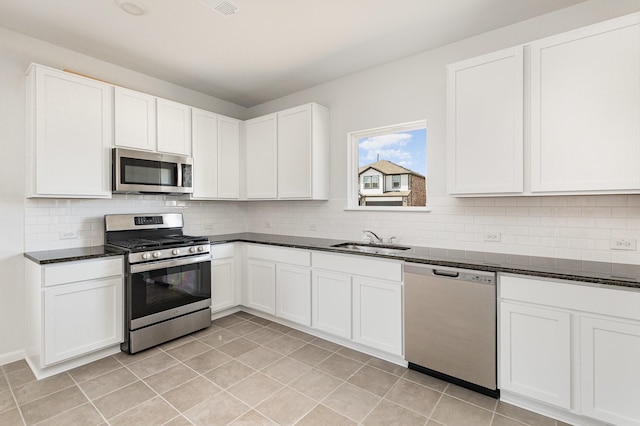 kitchen with decorative backsplash, a sink, white cabinets, stainless steel appliances, and light tile patterned flooring