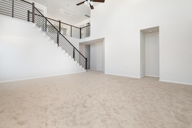 unfurnished living room featuring stairway, a high ceiling, carpet, and a ceiling fan