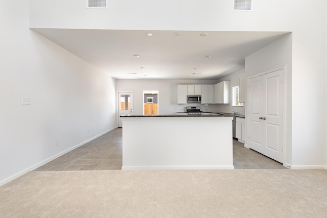 kitchen featuring visible vents, light carpet, dark countertops, white cabinets, and appliances with stainless steel finishes