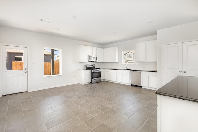 kitchen featuring tasteful backsplash, a sink, white cabinets, stainless steel appliances, and light tile patterned flooring