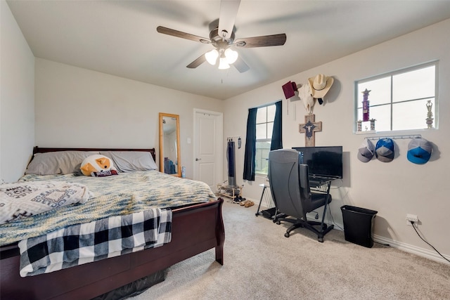 bedroom with light colored carpet, a ceiling fan, and baseboards