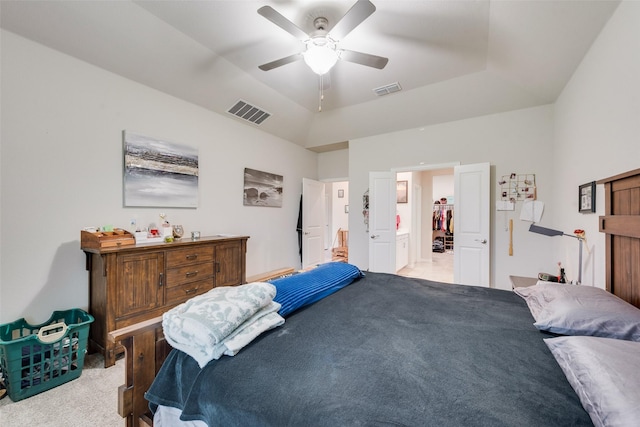 bedroom with light colored carpet, connected bathroom, a tray ceiling, and visible vents
