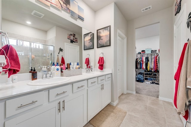 bathroom with double vanity, visible vents, a sink, and a stall shower