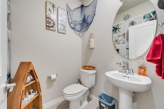 bathroom featuring a sink, tile patterned floors, baseboards, and toilet