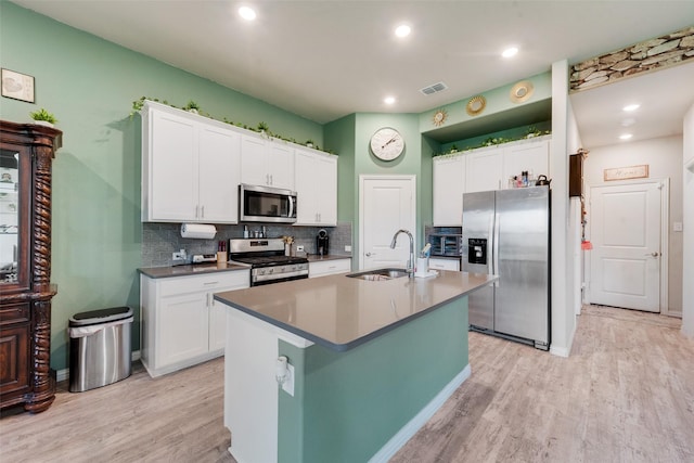 kitchen featuring white cabinets, a sink, stainless steel appliances, light wood-type flooring, and visible vents