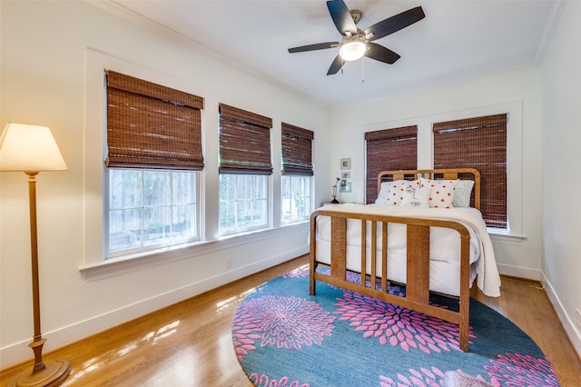 bedroom featuring crown molding, baseboards, ceiling fan, and wood finished floors