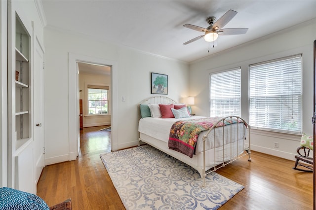 bedroom featuring crown molding, baseboards, and light wood-style flooring
